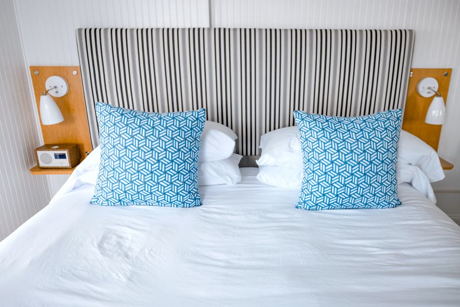Modern bedroom interior with striped headboard and blue geometric pillows, creating a cozy atmosphere.