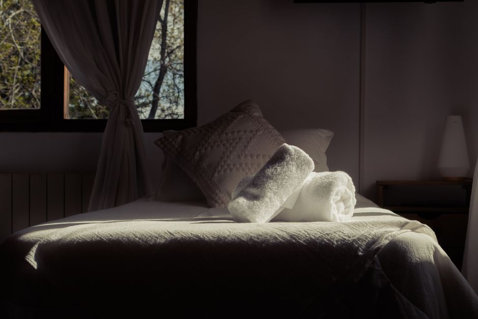 Inviting bedroom in San Carlos de Bariloche with towels on a bed and soft natural light through the window.