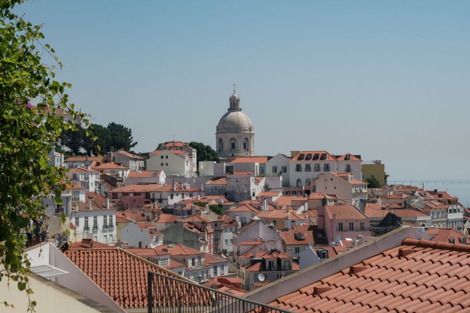 Beautiful view of Lisbon's traditional red rooftops with a prominent dome in the background.