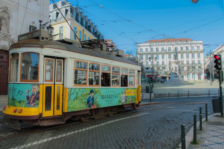 Iconic yellow tram on Lisbon streets with classic architecture backdrop.