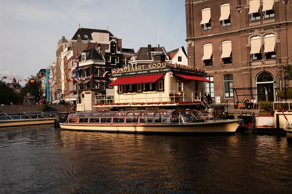 Daylight view of a classic canal boat and traditional buildings in Amsterdam.