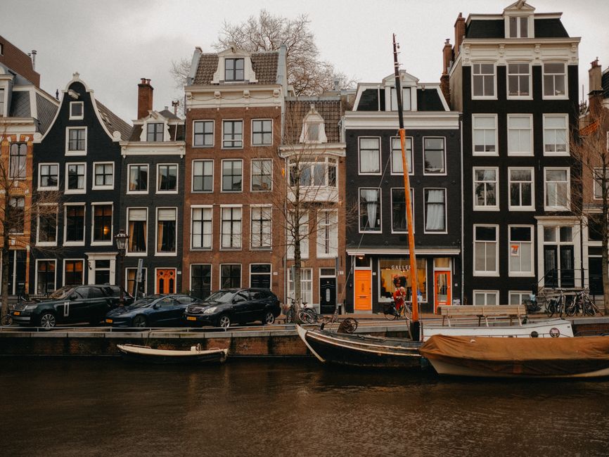 Picturesque Amsterdam canal scene with historic houses and moored boats.