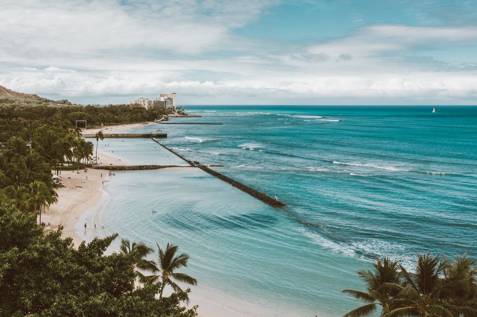 Stunning aerial shot of a tropical beach with palm trees and turquoise ocean waves.