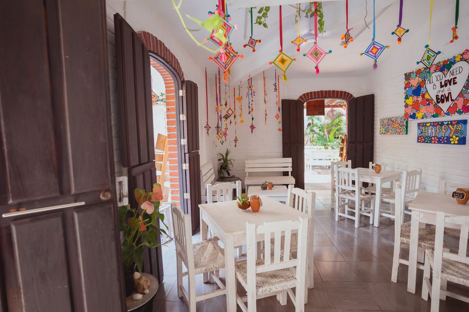Bright cafe interior featuring colorful hanging decorations and white furniture with natural light.