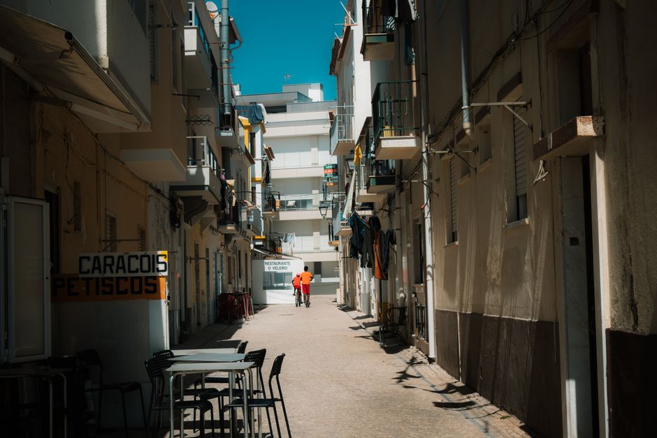 Quiet alley in Nazaré, Portugal with outdoor seating and traditional architecture.