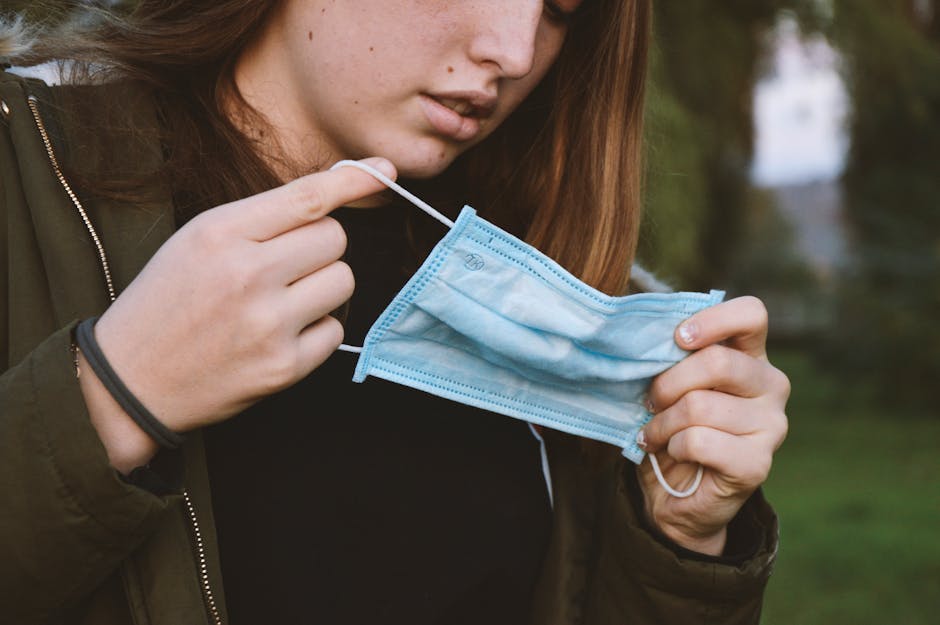 Young woman holding a face mask outdoors, representing health and safety measures.