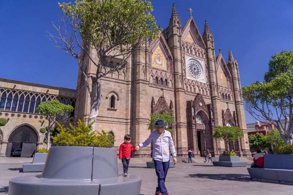 A father and son walk hand in hand by a beautiful Gothic cathedral on a sunny day.
