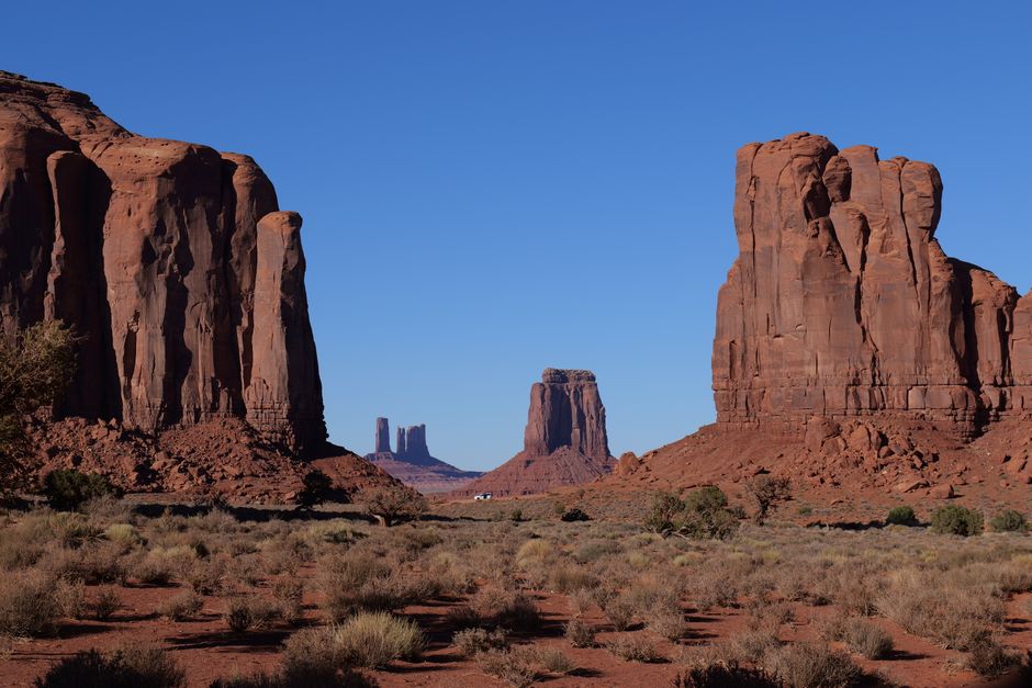 Stunning view of iconic red rock formations in Monument Valley under clear blue skies.