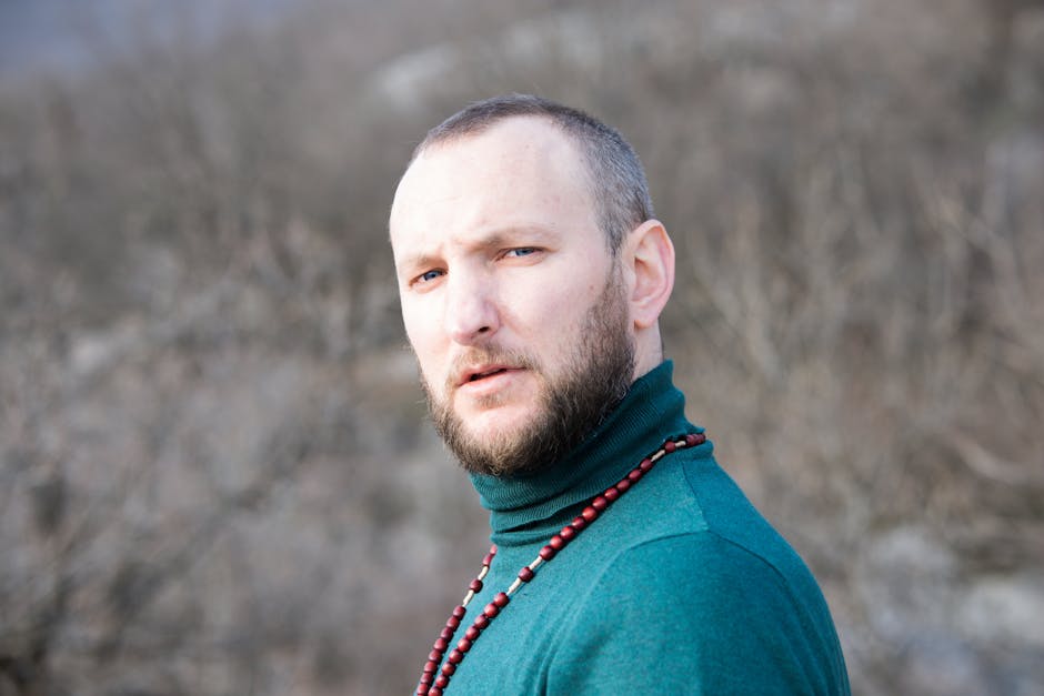 Bearded man wearing green sweater in Podgorica, Montenegro's winter landscape.