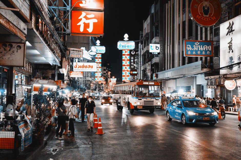 Lively street scene at night with bright signs and busy traffic in a bustling city.